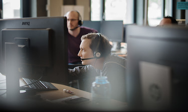 Mann mit Headset am Monitor Collaborateur avec casque audio